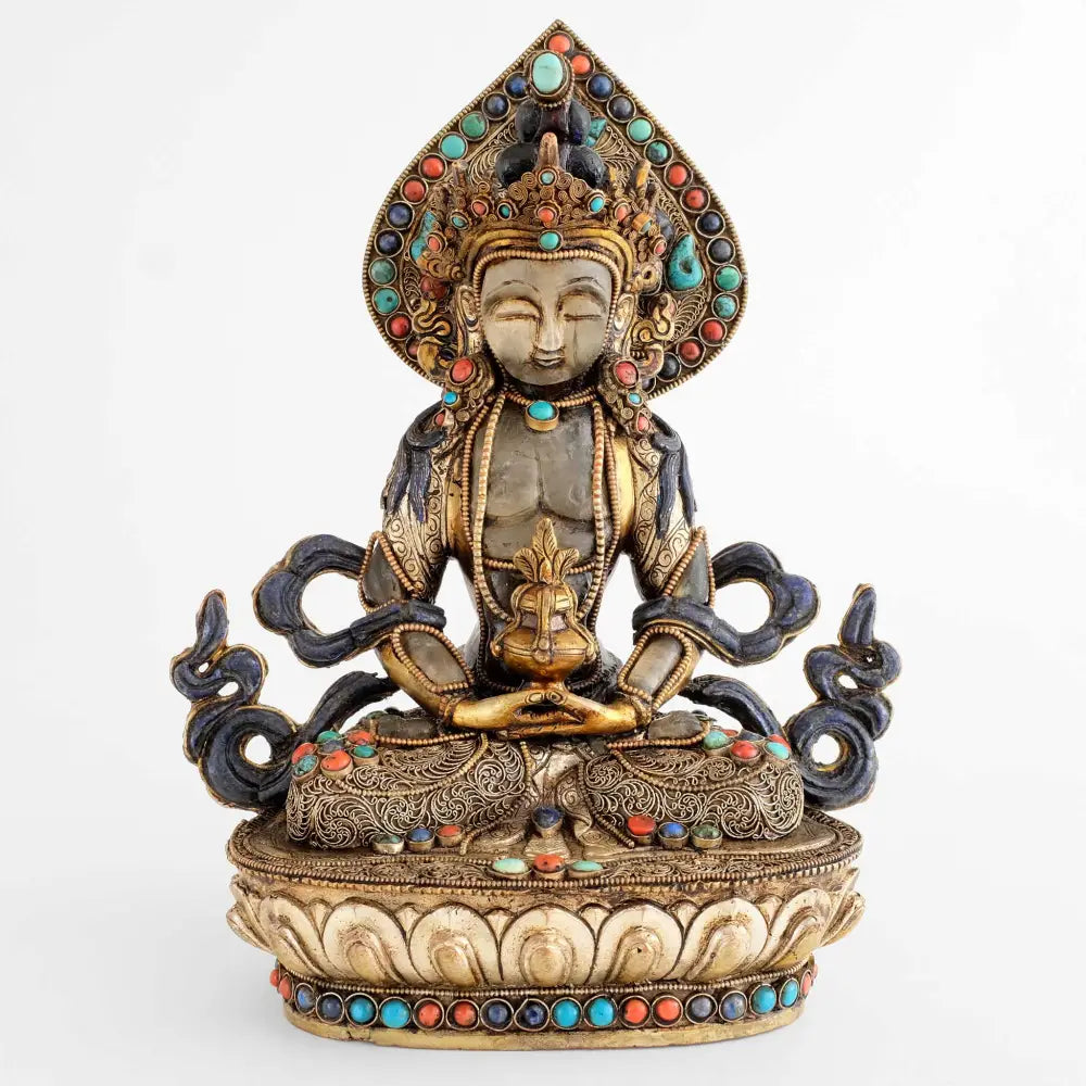 Amitayus Figur, aus Kupfer gegossen, Kopf und Körper aus Kristall geschnitzt, verziert mit feinen Filligranmotiven, versilbert und vergoldet, besetzt mit Lapislazuli, Koralle und Türkis.