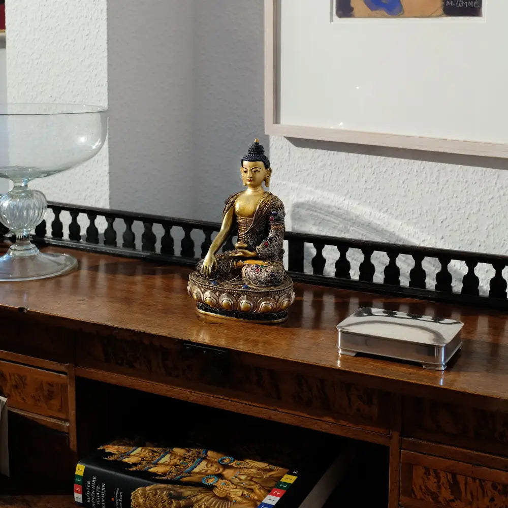 Buddha Shakyamuni oder Siddhartha Gautama auf einem antiken Schreibtisch. Beispiel einer kostbaren spirituellen Dekoration.