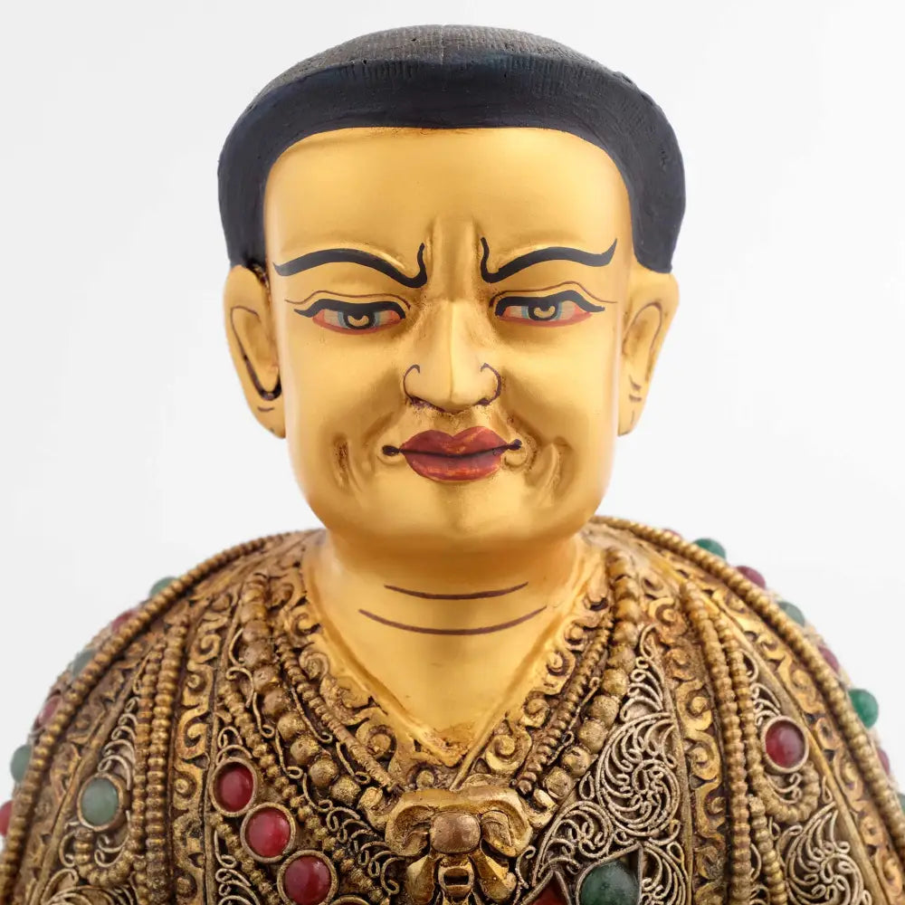 Guru Marpa, der Übersetzer. Detail seines in Gold gefassten Gesichts. Sein Gesichtsausdruck verbindet Strenge und Güte eines herausragenden Lehrers. Seine Robe ist reich verziert, so wie traditionelle königliche Gewändern.