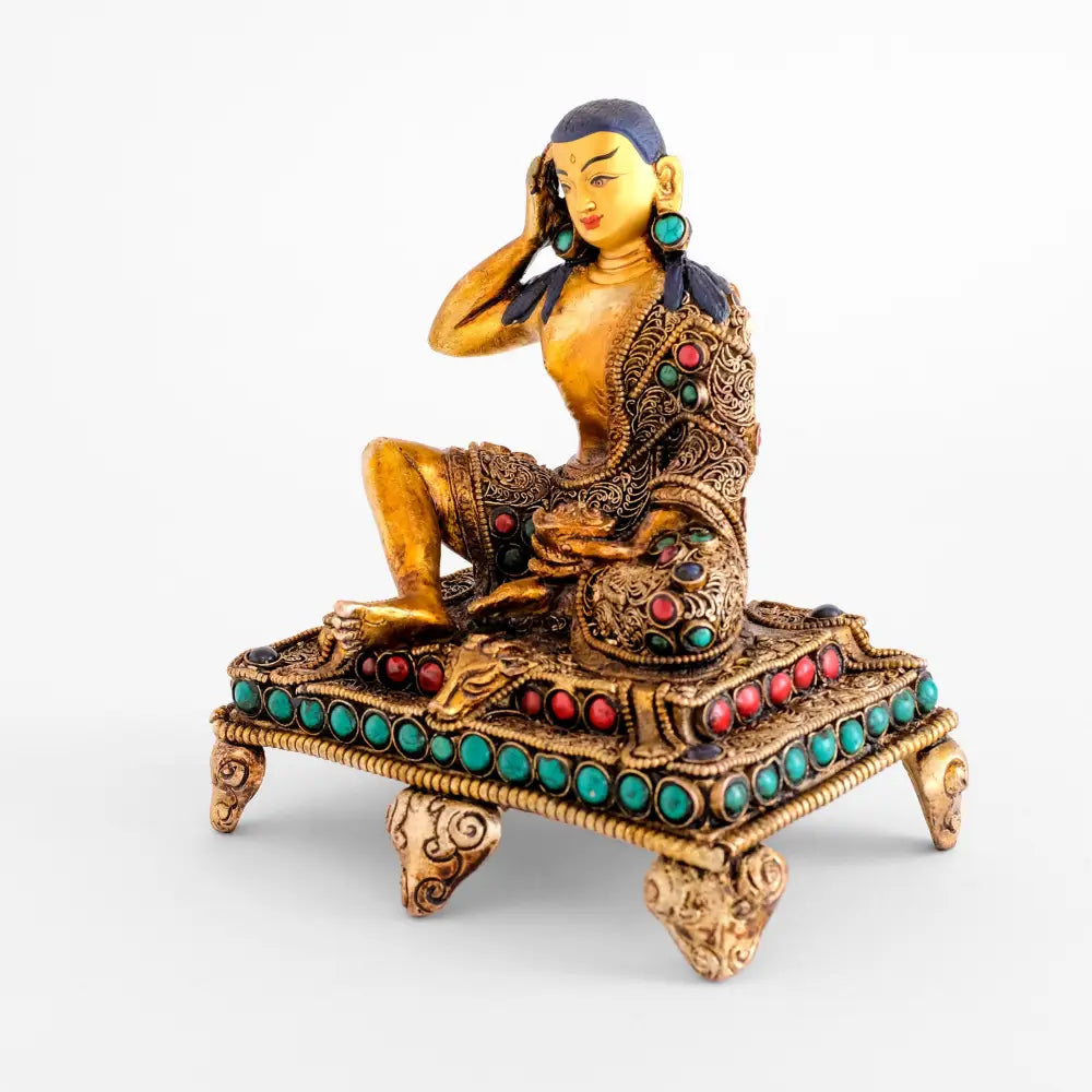 Milarepa wird in Ardhaparyanka Asana auf einem Gazellenfell sitzend dargestellt. Jetsun Milarepa ist auch als tibetischer Buddha bekannt. Er hält die rechte Hand an sein rechtes Ohr, die linke Hand hält eine Schale.