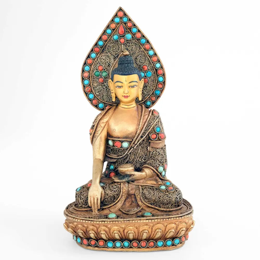 Shakyamuni Buddha Statue mit tropfenförmigem Nimbus. Der Hintergrund ist besetzt mit versilbertem Filigran in spiralförmigen Elementen. Die Figur ist mit Türkisen ud Korallen akzentuiert.