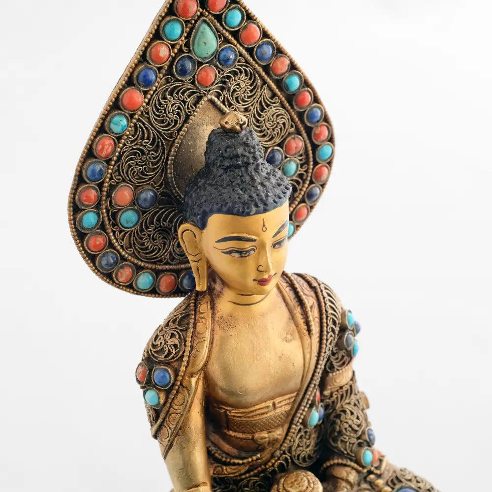 Buddha Statue mit Nimbus. Der Nimbus und seine Robe sind mit feinen Filigranornamenten in Spiralform besetzt. Mit farbigen Steinen akzentuiert.