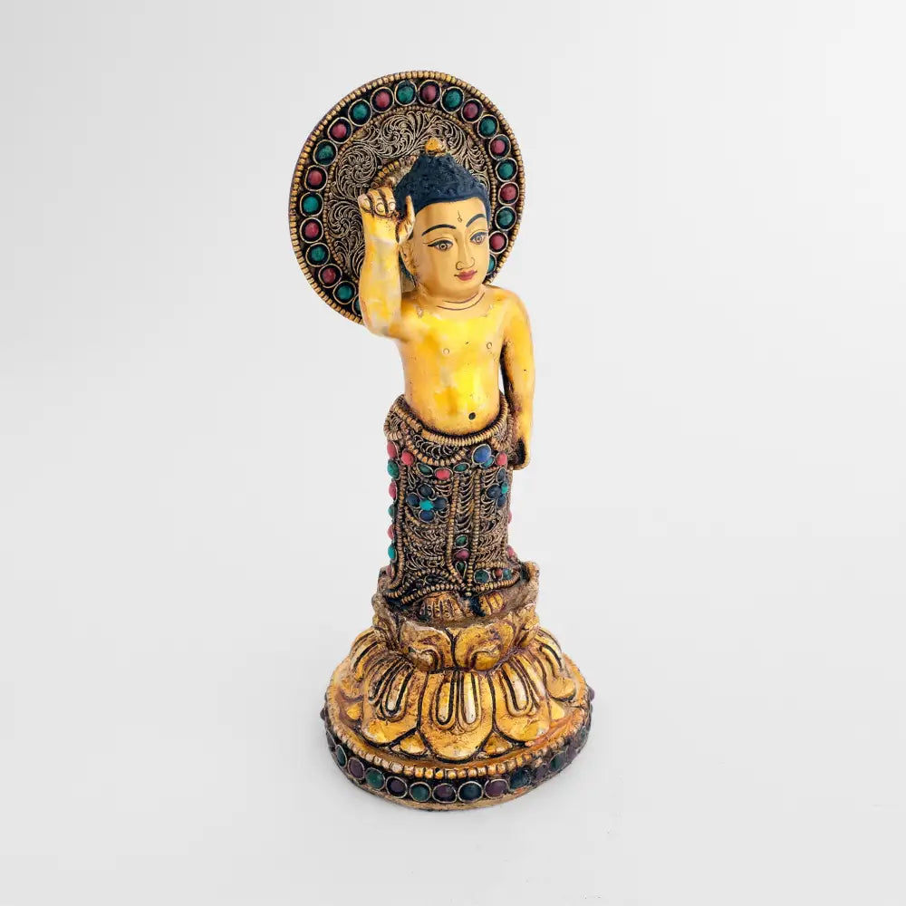 Buddha als Kind. Er steht auf einer Lotosblüte und hält seinen rechten Zeigefinger hoch. Hinter seinem Kopf ein kreisförmiger Nimbus.