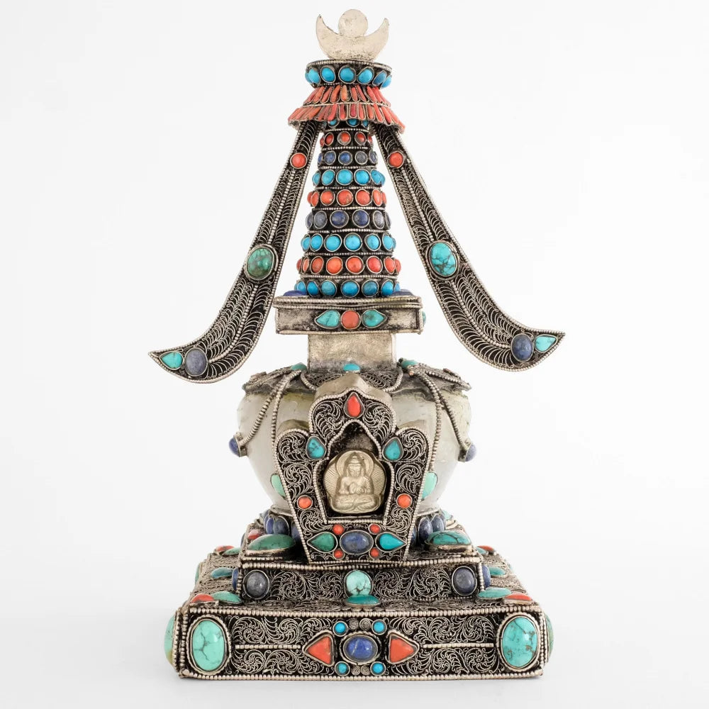 Stupa, in tibetischem Chörten, Vorderansicht. Sie ist aus Kupferplatten gefertigt, verziert mit feinen, spiralförmigen Filigranornamenten, versilbert und mit Edelsteinen besetzt. Die Kuppel ist aus Kristall.