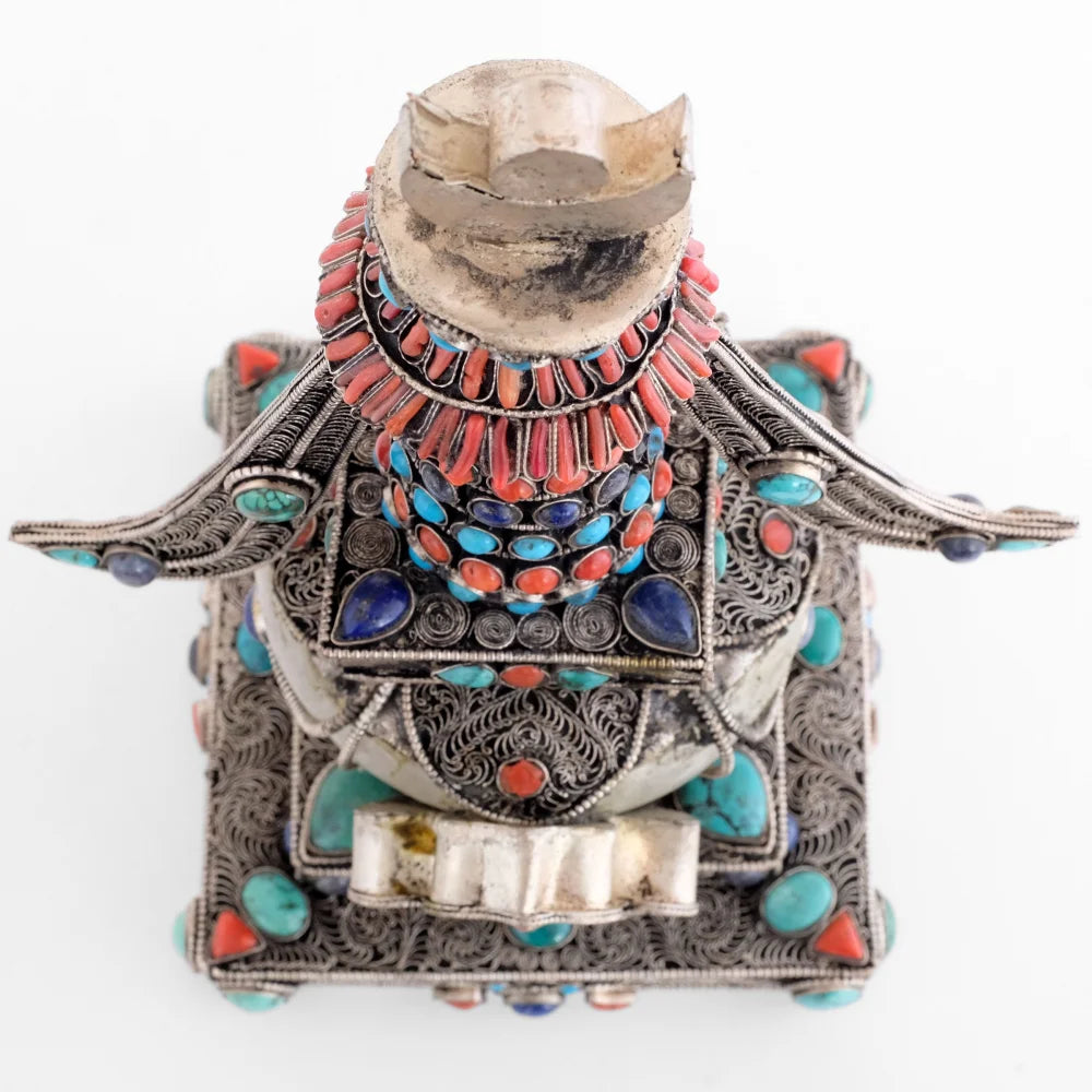 Stupa, Chorten, Ansicht von oben. Ihr Schirm ist mit Korallen verziert, die quadratische Harmika hat in jeder Ecke einen tropfenförmigen Lapislazuli-Stein, die Kuppel ist mit vier filigranen Bögen verziert, der quadratische Sockel ist ebenfalls mit in Spiralen angeordnetem Filigran verziert.