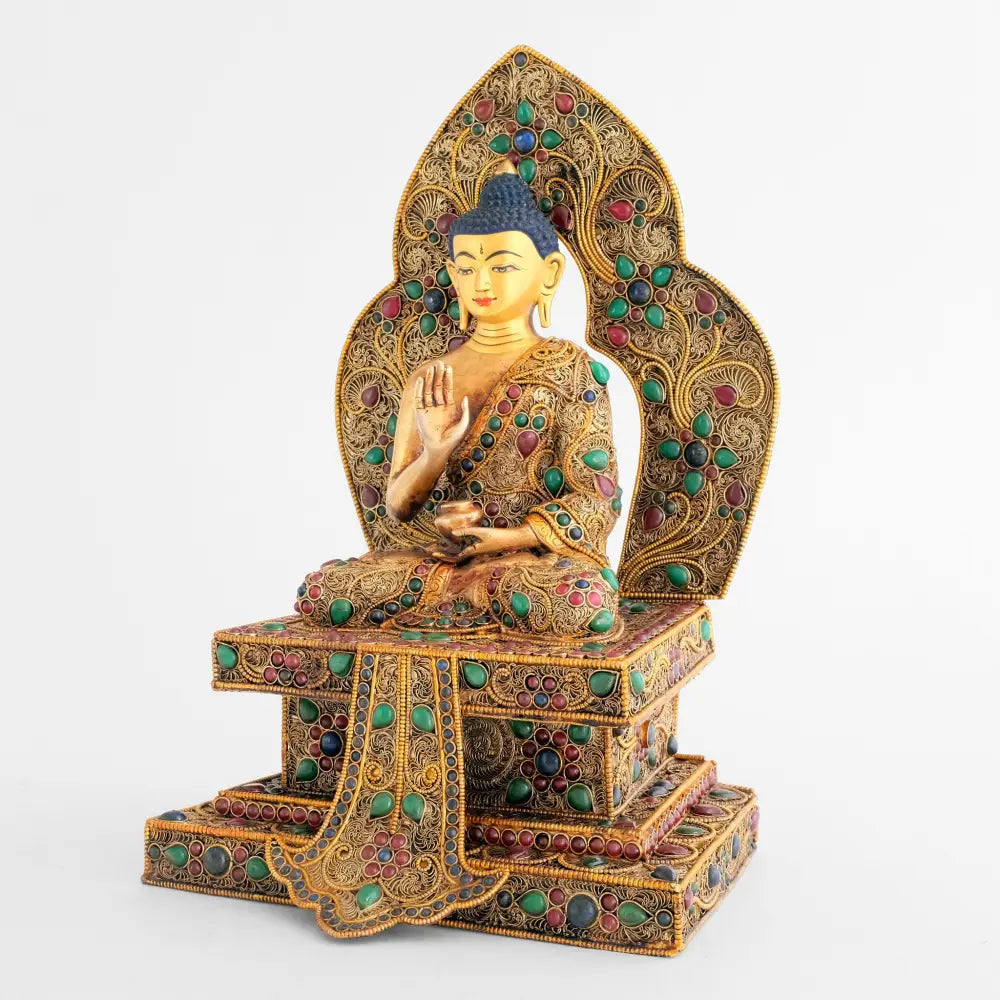 Amoghsiddhi Buddha Statue, verziert mit Filigran und farbigen Steinen. In der Mitte des Sockels ist ein buddhistisches Patuk Banner angebracht.