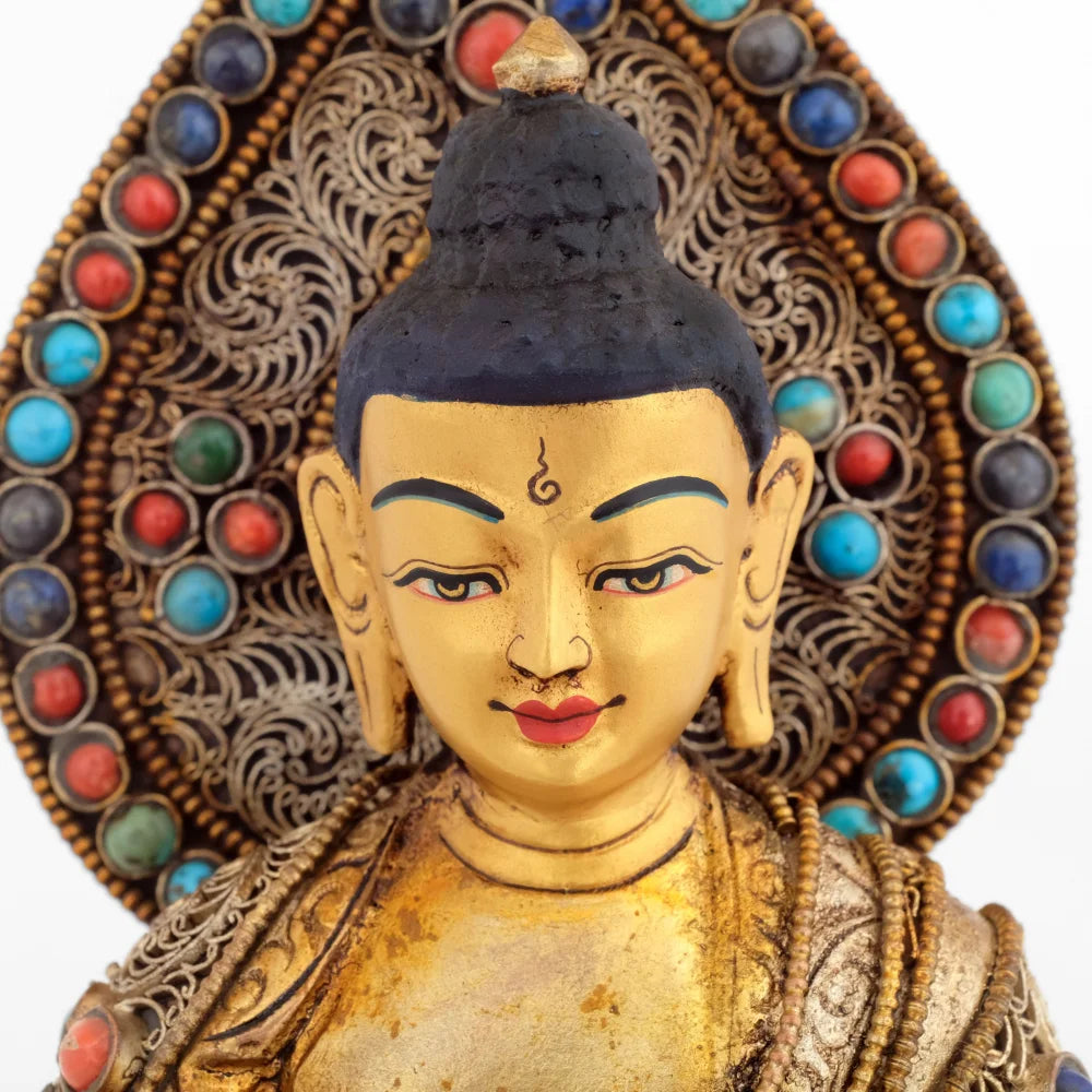 Das Gesicht des Bhaisajyaguru, Medizin Buddhas ist in Gold gefasst. Hinter seinem Kopf eine verzierte tropfenförmige Aureole.