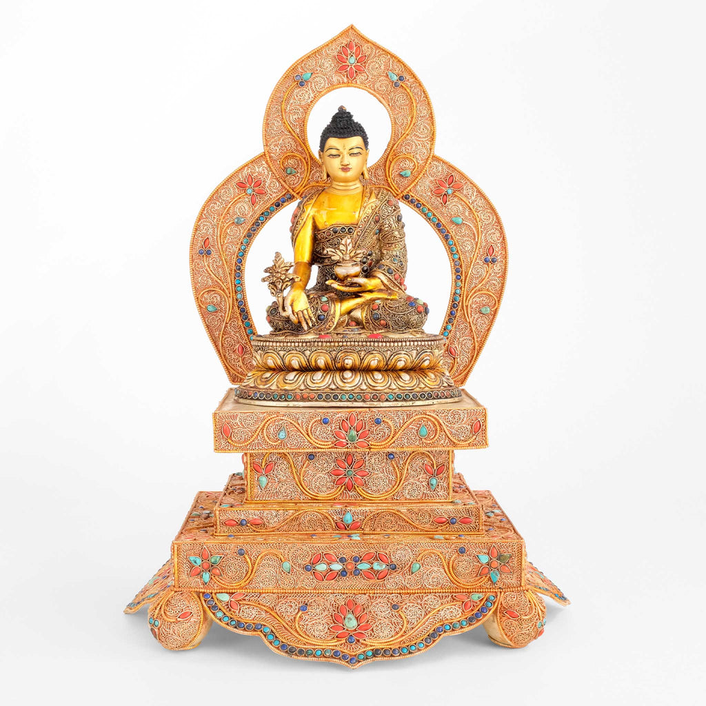 Bhaisajyaguru, Medizin Buddha Statue in Filigran gearbeitet, mit farbigen Steinen besetzt. Auf Thron mit Aureole.