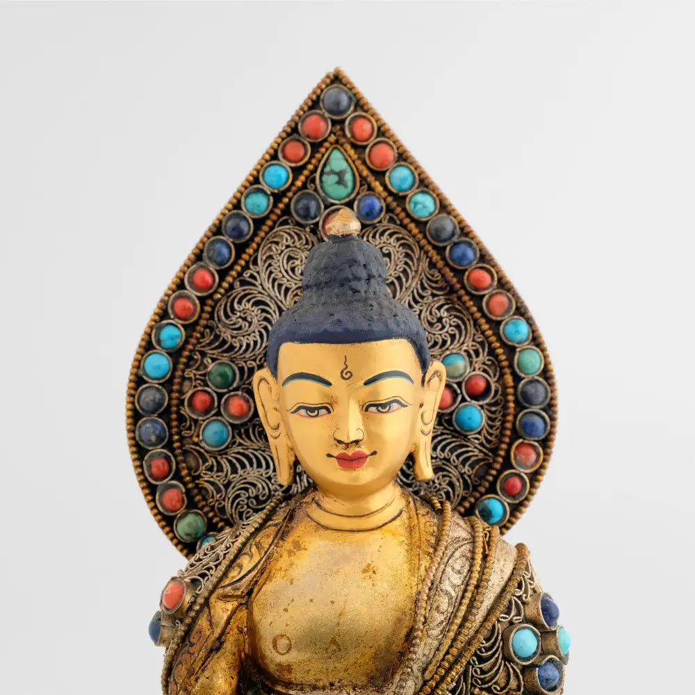 Detail der Medizin Buddha Figur mit Hintergrund, tropfenförmigem Nimbus. Nimbus und Robbe sind besetzt mit feinen Filigran Ornamenten in spiralförmiger Anordnung.