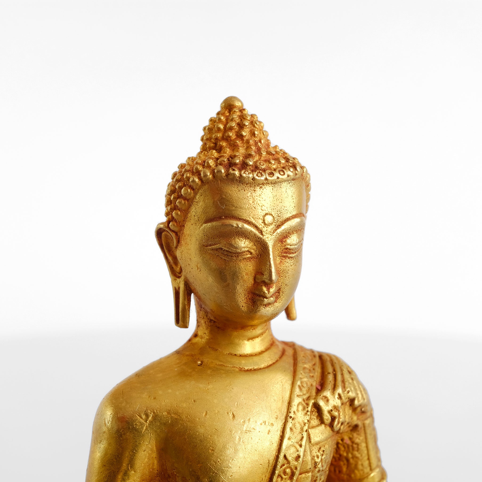 Detail der kleinen Buddha Statue aus vergoldetem Kupfer. Detaillierter Guss. Für das Finish mit rotem, Vermillion Pulver bestäubt.