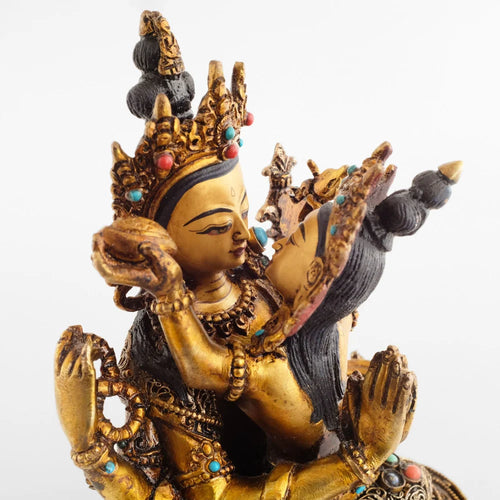 Chenrezig-Statue in Yab Yum. Avalokitesvara und seine Shakti schauen sich an. Seine Arme umarmen sie und seine Hände berühren sich mit den Handflächen hinter ihrem Rücken.