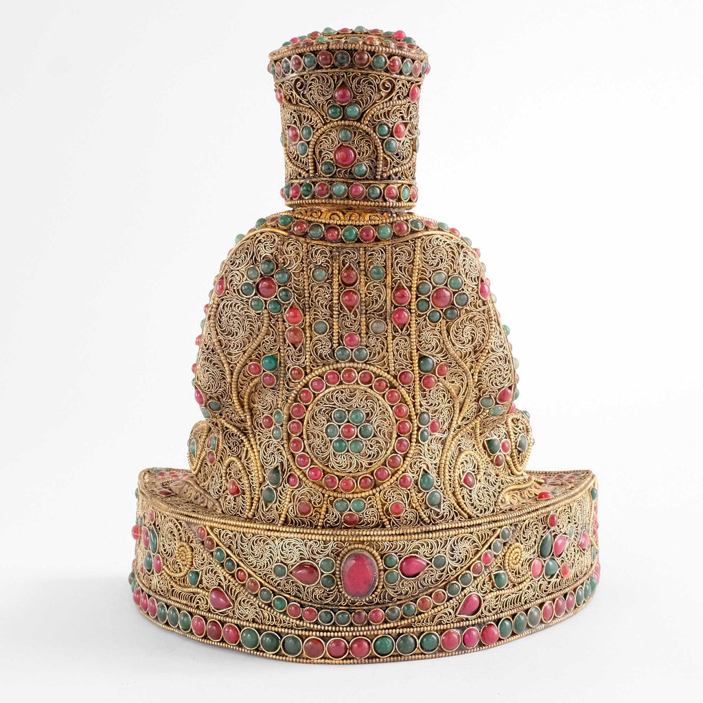 Gampopa Statue, Rückenansicht. Seine Robe zeigt eine Rosette unnd in senkrechten Streifen angeordnetes Filigran mit floralen Elementen. In Bordüren wechseln sich rote und grüne Steine ab.