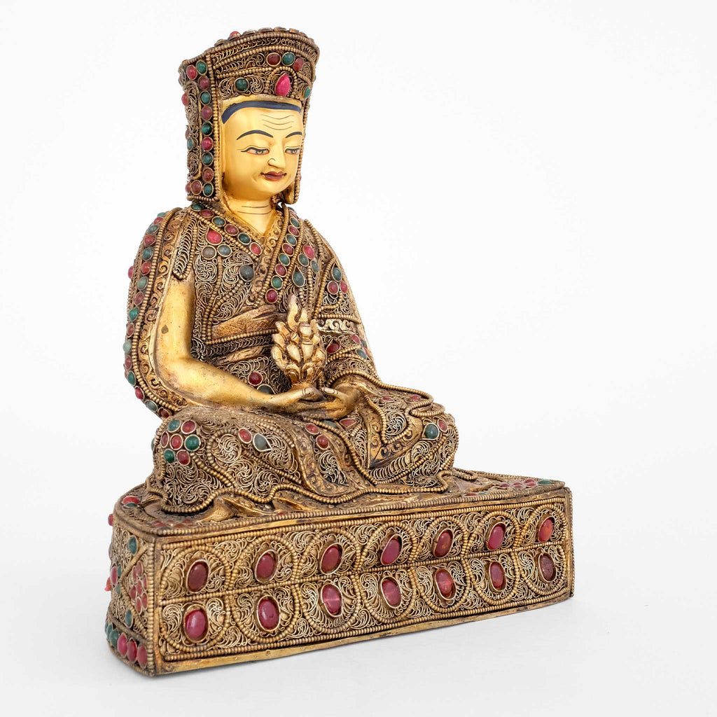 Seitenansicht Gampopa Sonam Rinchen Statue. Sein Gewand und der Sockel sind mit Filigran gestaltet, vergoldet und versilbert, mit farbigen Steinen besetzt.
