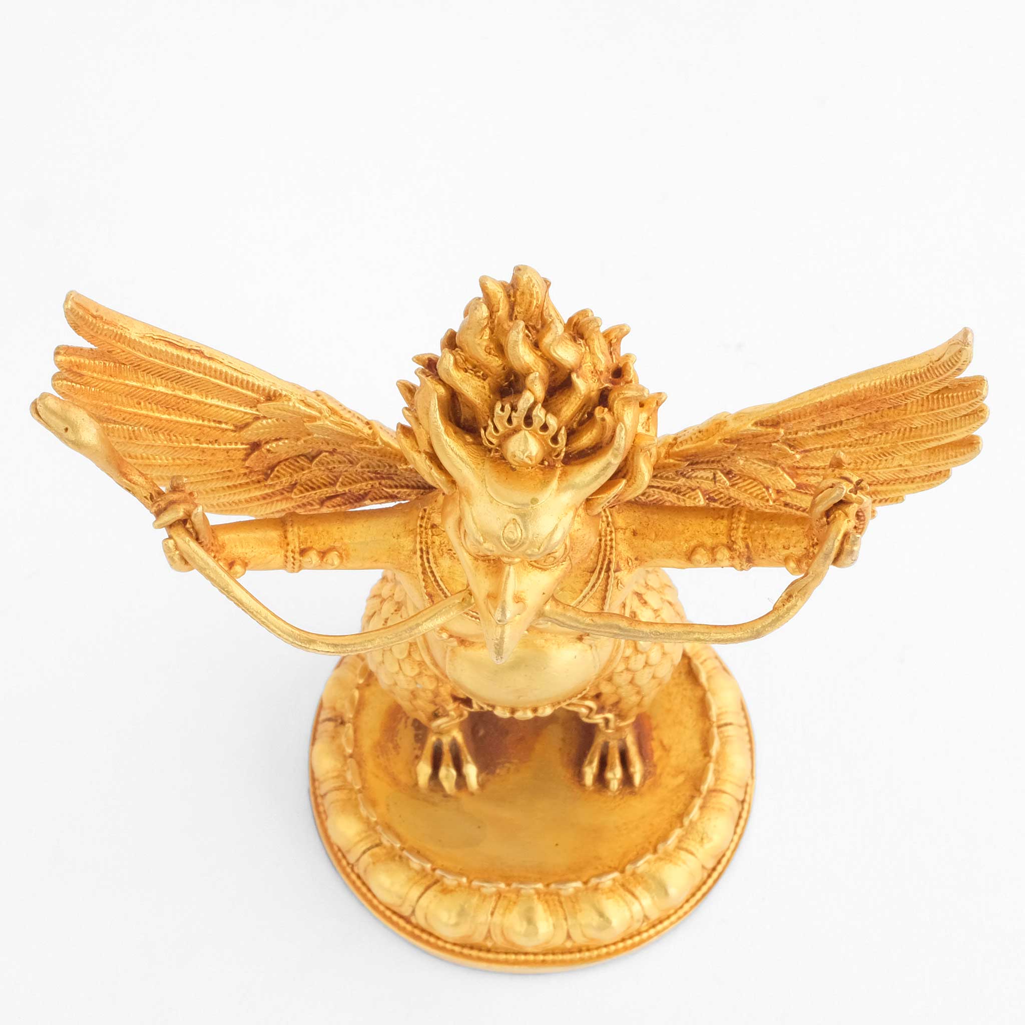 Kleine vergoldete Garuda Statue in der Aufsicht. Er steht mit ausgebreiteten Flügeln und hält eine Naga im Schnabel.