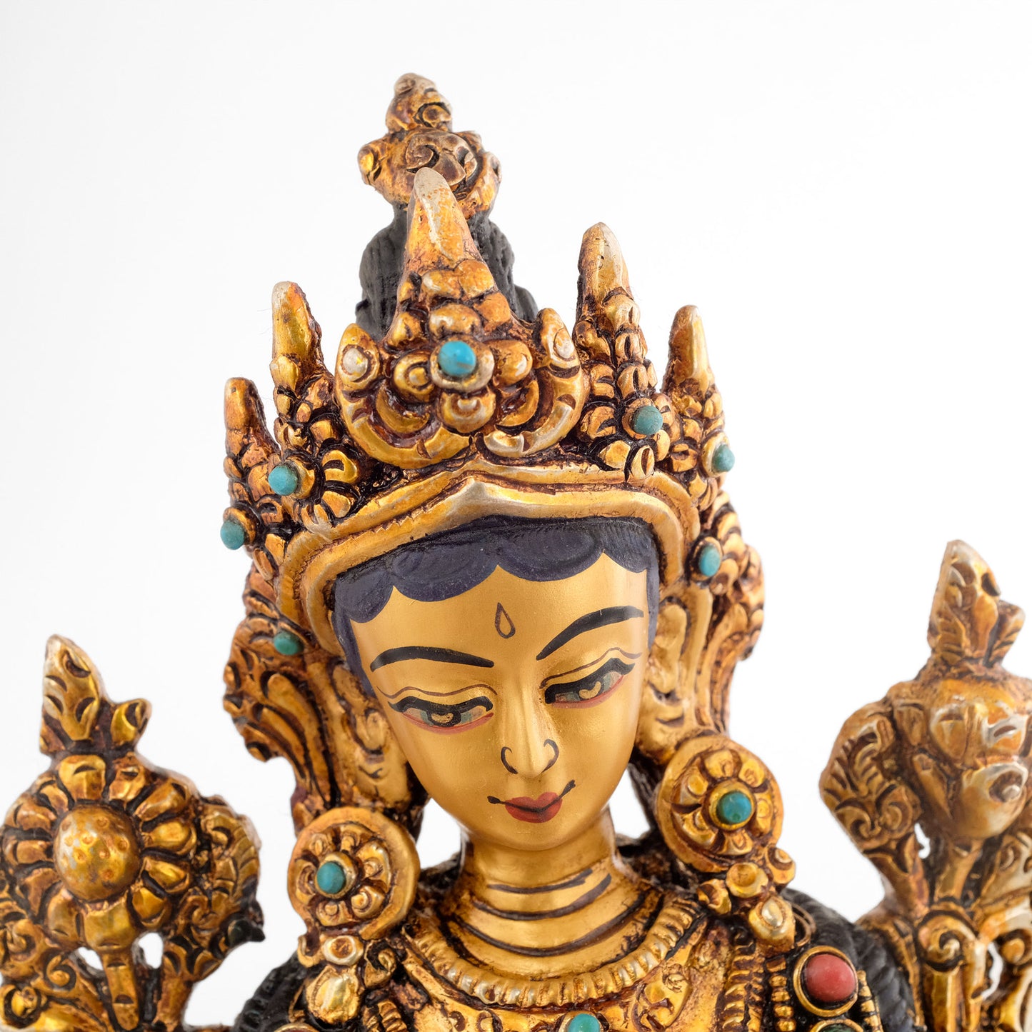 Grüne Tara statue mit 5-zackiger Krone und reichem Schmuck eines Bodhisattvas. Hier das Detail des Gesichts. Es ist in Gold gefasst.