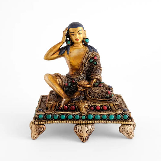 Milarepa statue, die Figur sitzt auf einem niedrigen Sockelthron. Der Tron und das Gazellenfell sind verziert mit feinem Filigran und mit farbigen Steinen besetzt.