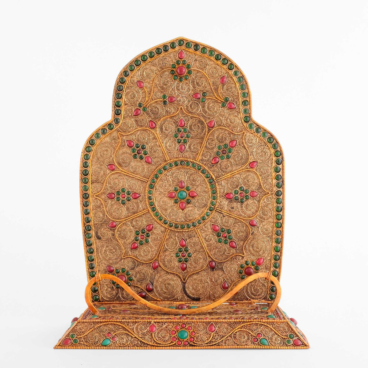 Detailansicht der Kartika-Rückwand, mit Filigran gestaltet und einer achtblättrigen Lotusblüte als zentralem Motiv, umrahmt von einer Reihe dunkelgrüner Steine. Im Vordergrund die geschwungene Halterung.
