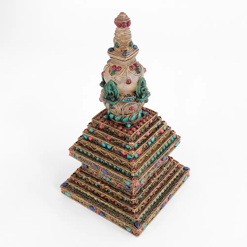 Verzierte, gestufte Stupa mit farbigen Steinen akzentuiert.