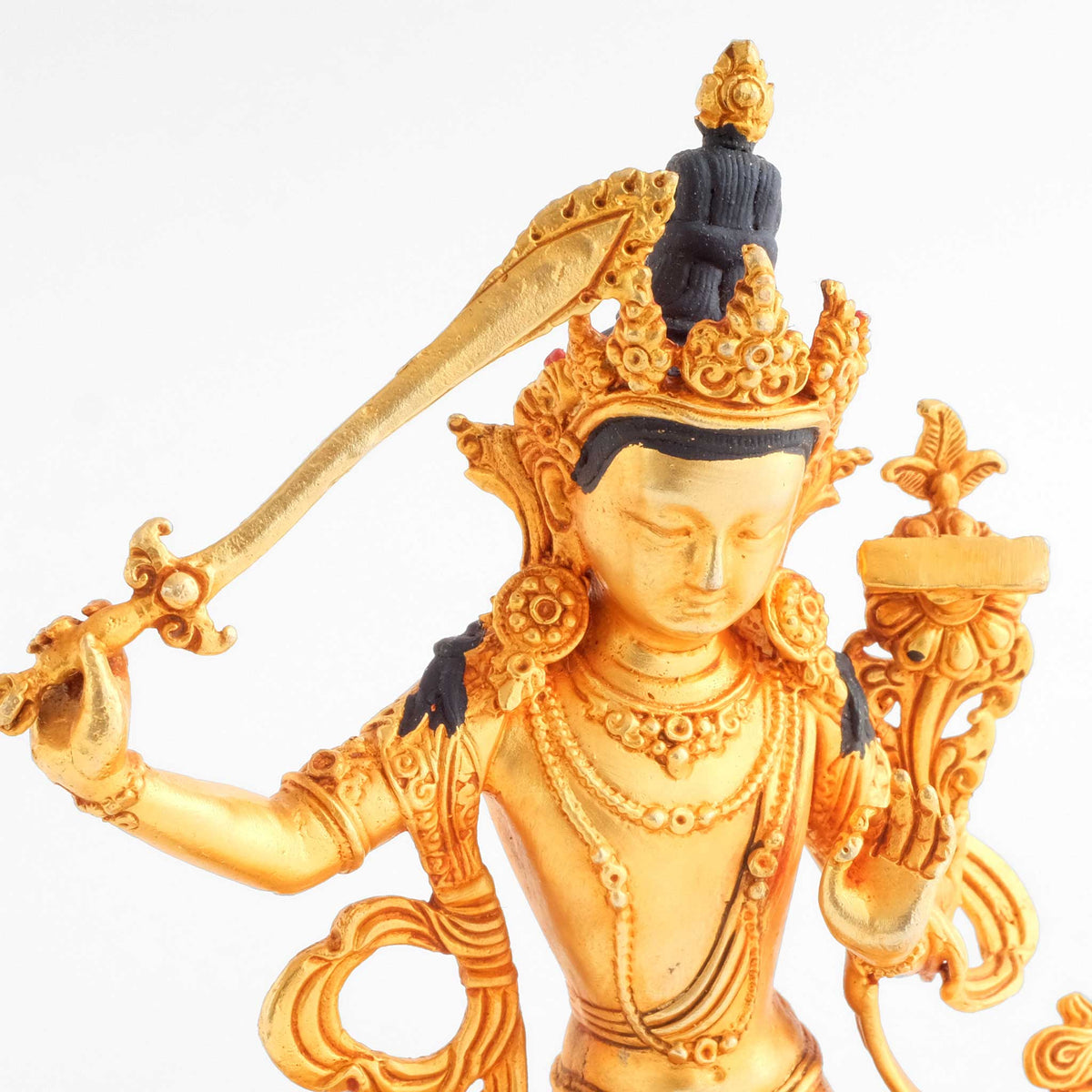 Manjushri Statue, kleine vergoldete Figur, detaillierter Kupferguss. Detailaufnahme mit Schwert, Krone und Gesicht.