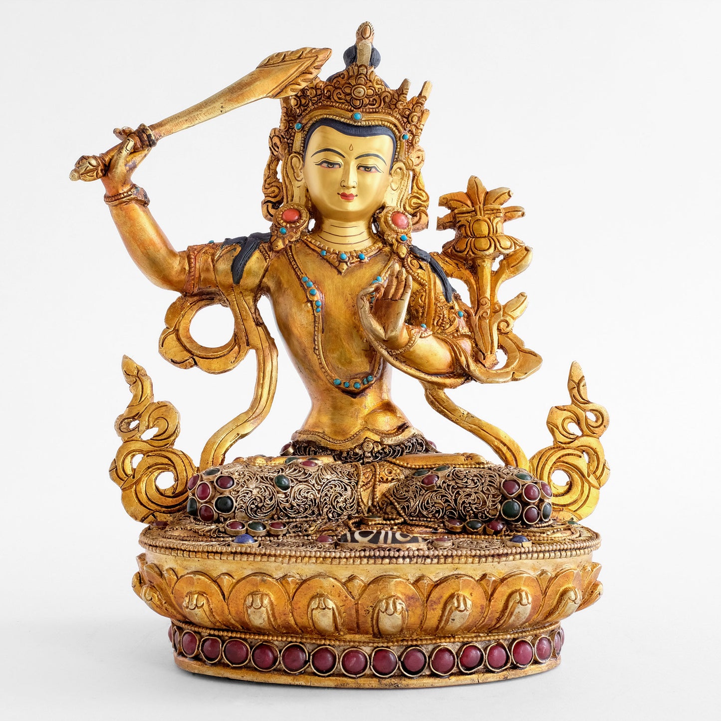 Manjushri statue from front. Gold plated figure, the god of wisdom holds the flamed sword in his right hand and the Prajnaparamita with a lotus flower on his right shoulder.