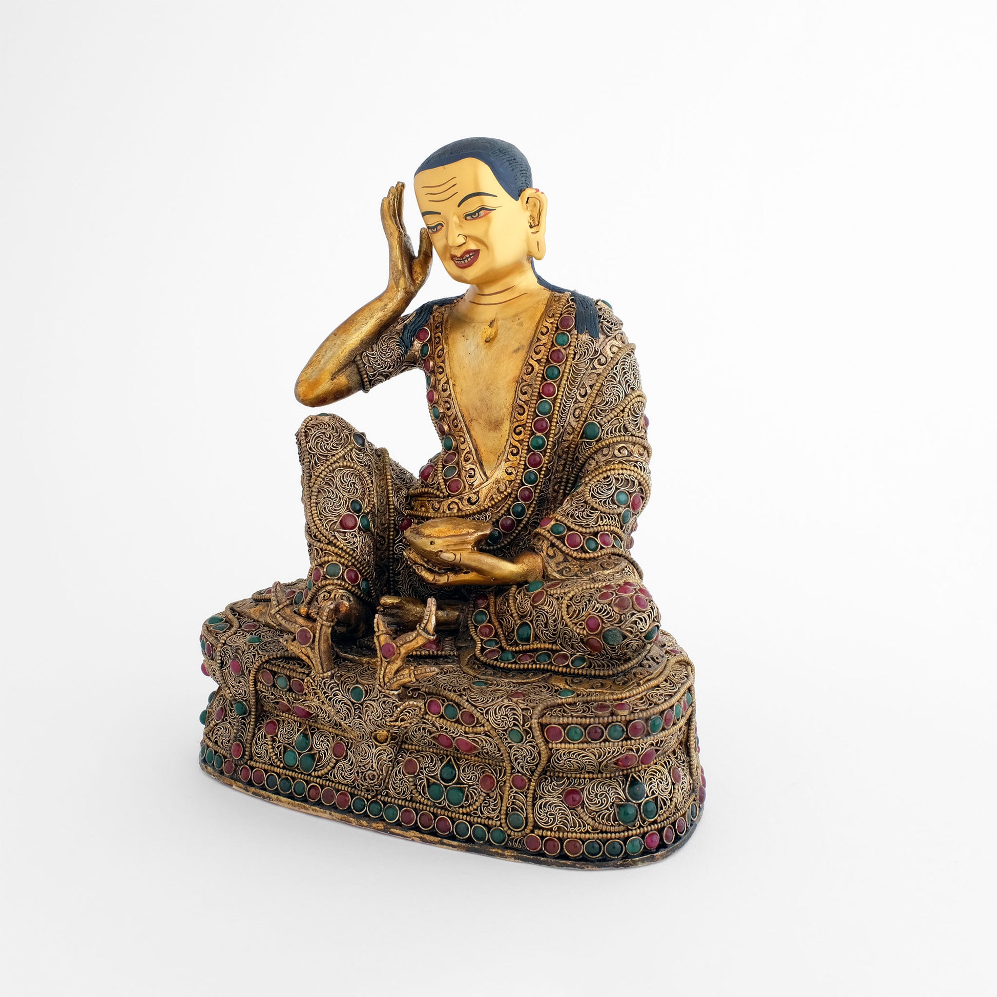 Jetsun Milarepa Figur, die rechte Hand hält er an sein rechtes Ohr, in seiner linken Hand hält er einen Tontopf. Vorn an seinem Thron sieht man den Kopf einer Himalaya Gazelle auf deren Fell der Gelehrte sitzt. 