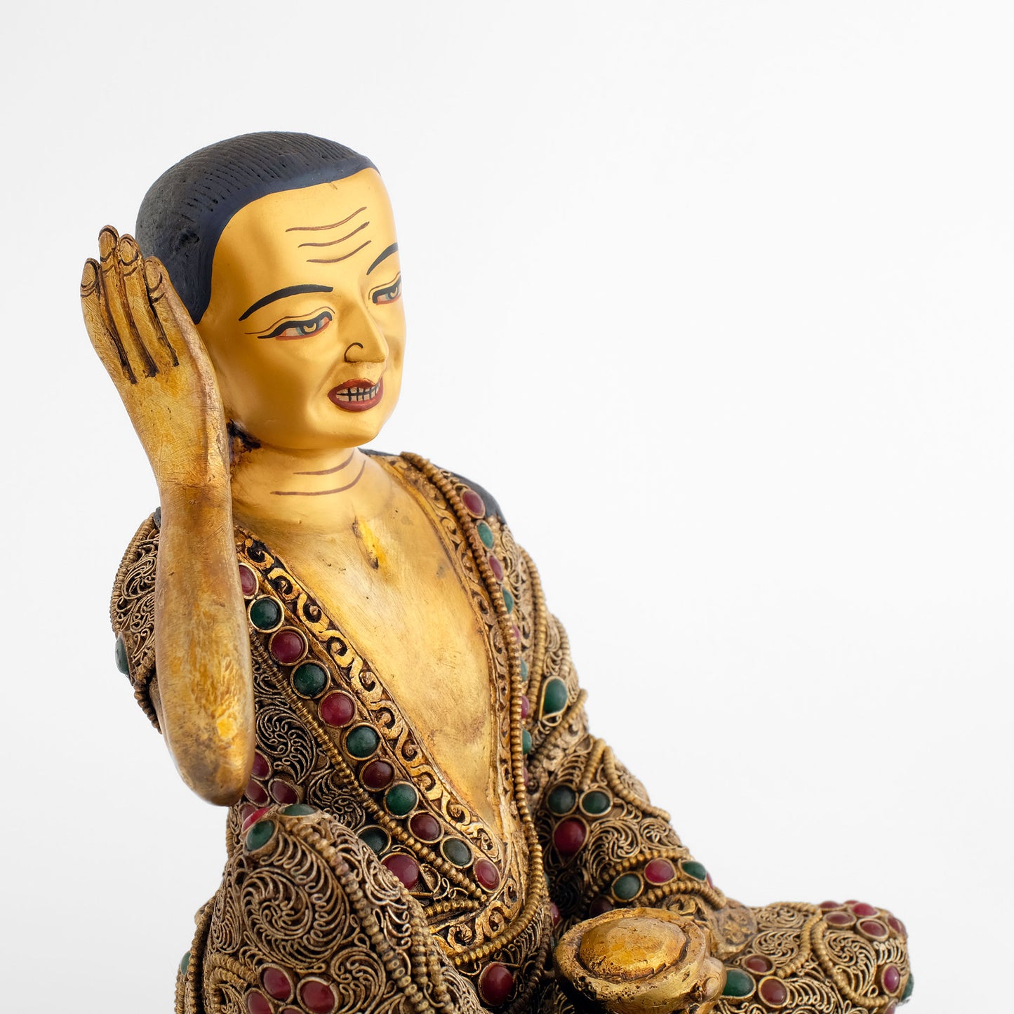 Jetsun Milarepa Statue, das Gesicht ist in Gold gefasst, seine rechte Hand am rechten Ohr, sein Gewand ist mit feinen spiralförmigen Filigran Elementen und farbigen Schmucksteinen verziert.