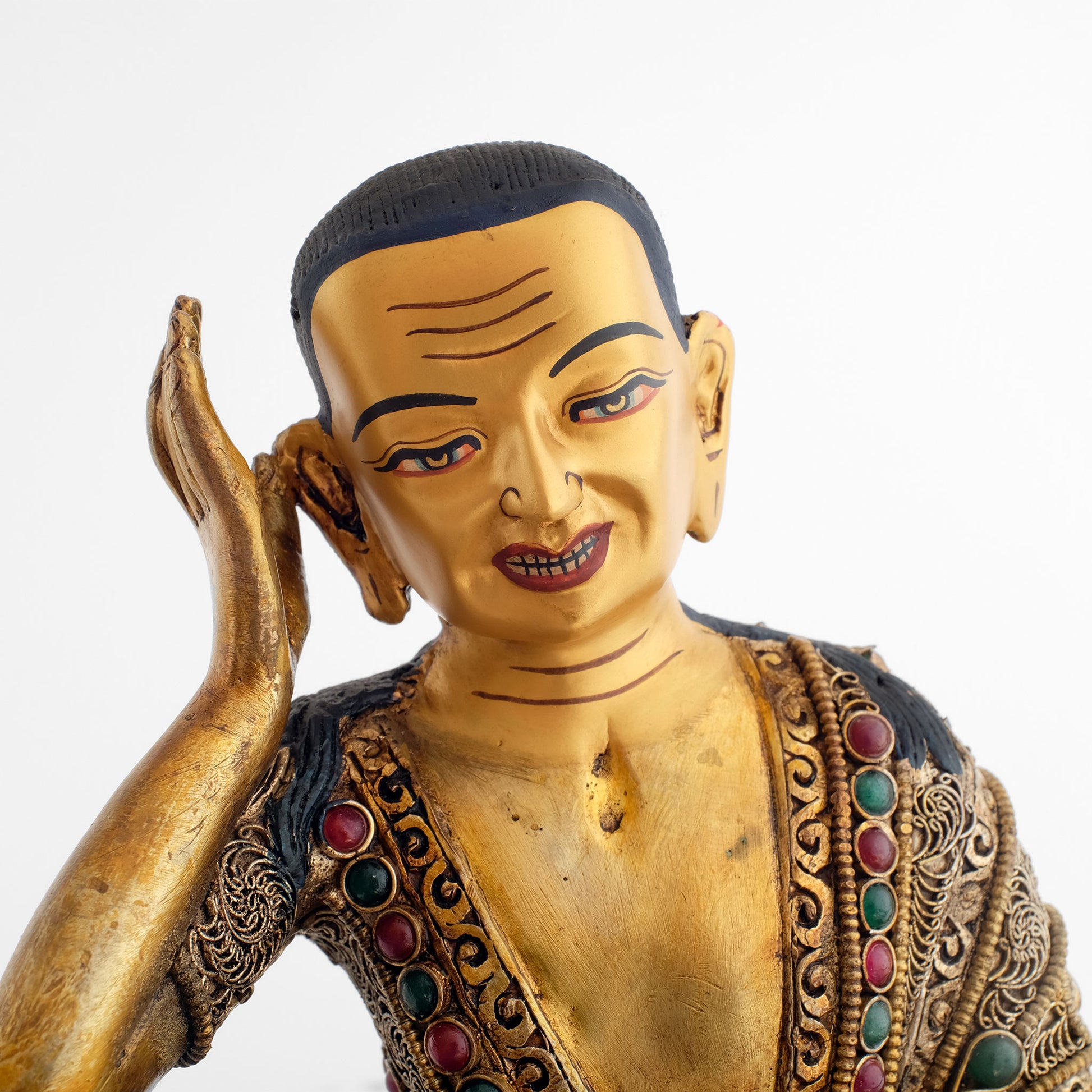 Milarepa statue, Detail des Gesichts, in Gold gefasst. Seine rechte Hand hält er mit ausgestreckten Fingern hinter dem rechten Ohr, als würde er dem Echo der Natur lauschen.