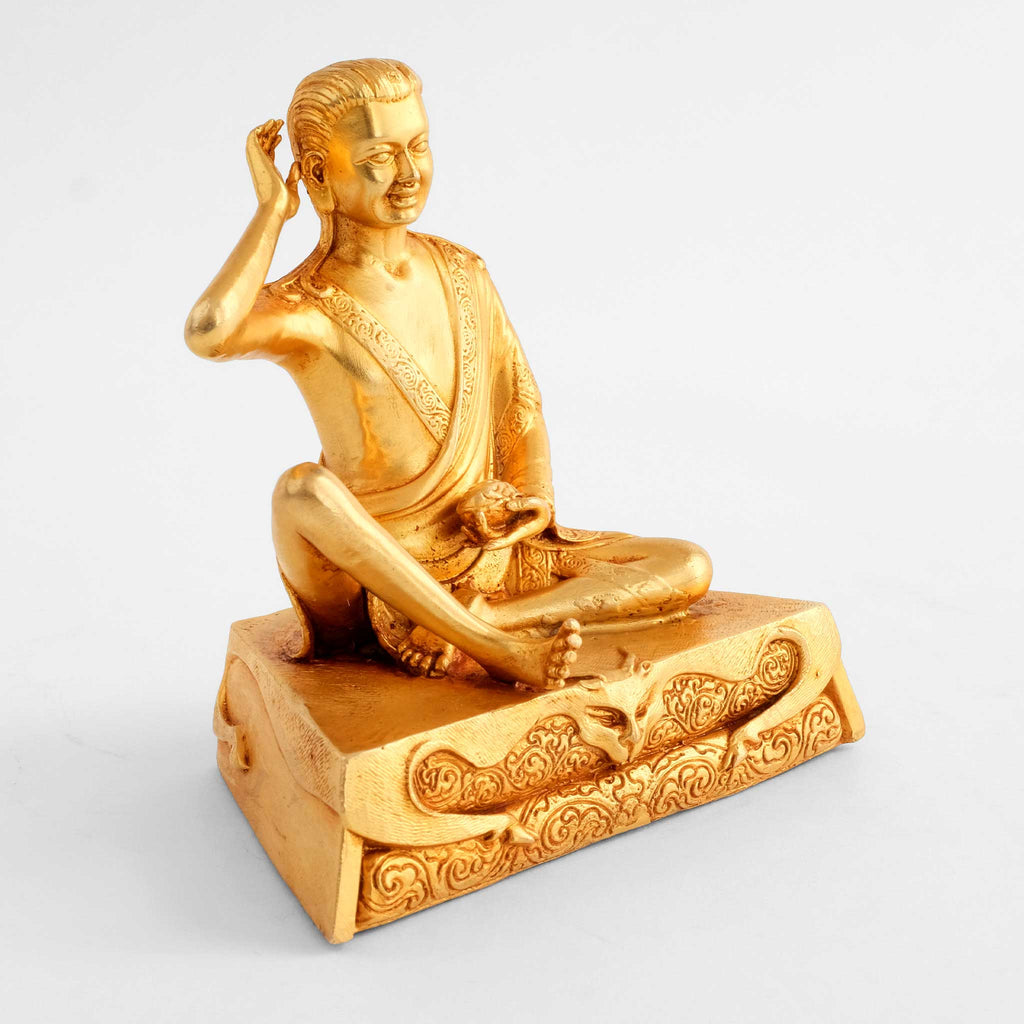 Milarepa Statue, auf einem eckigen Sockel, die rechte Hand am Ohr. Vergoldete buddhistische Figur.