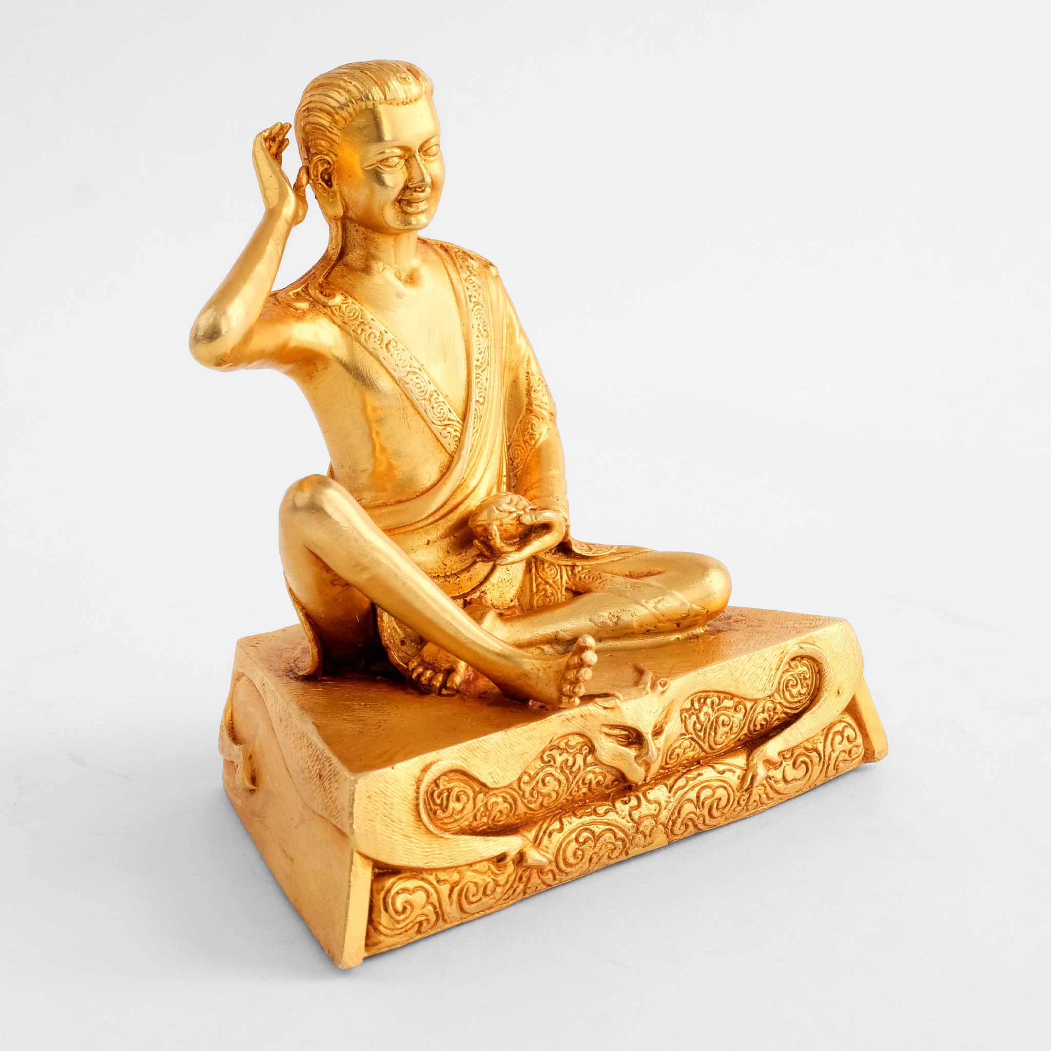 Milarepa Statue, auf einem eckigen Sockel, die rechte Hand am Ohr. Vergoldete buddhistische Figur.