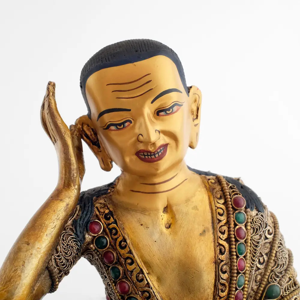 Milarepa statue, Detail des Gesichts, in Gold gefasst. Seine rechte Hand hält er mit ausgestreckten Fingern hinter dem rechten Ohr, als würde er dem Echo der Natur lauschen.