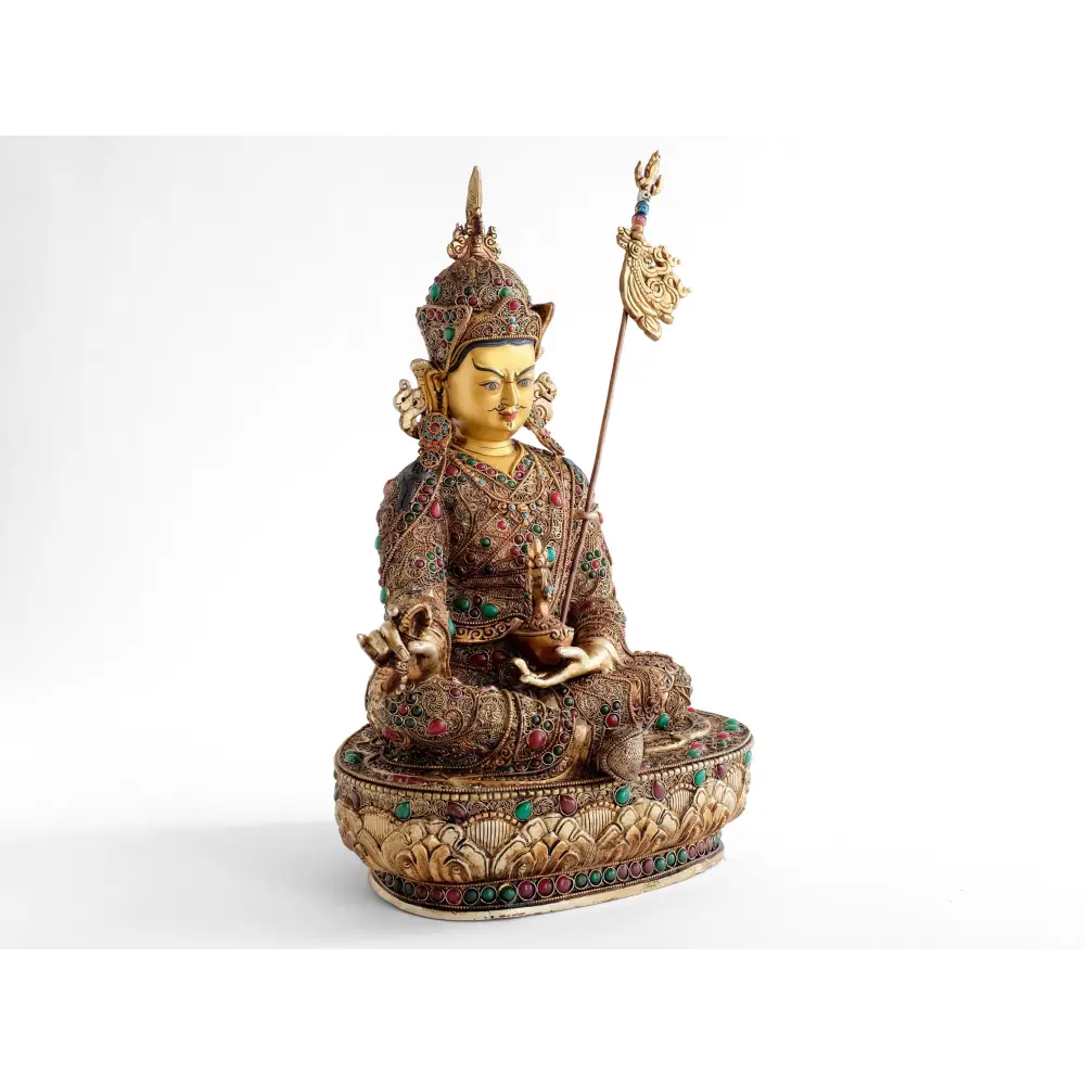 Padmasambhava, der Lotusgeborene, er ist auch als Guru Rinpoche bekannt. Er sitzt in Lalitasana, seinen Stab Khatvanga an seiner linken Seite. In seiner linken Hand, die er in den Schoß legt, hält er eine Schädelschale, mit der Langlebigkeits Vase Amrita.