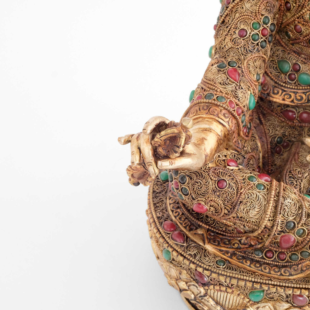 Guru Rinpoche, Padmasambhava, hält einen Vajra in seiner rechten Hand. Detail der Hand und des Filigran.