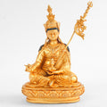 Kleine vergoldete Statue von Padmasambhava (Guru Rinpoche), die in traditioneller Haltung auf einem Lotussockel sitzt, fein detailliert und als freistehendes Objekt dargestellt.