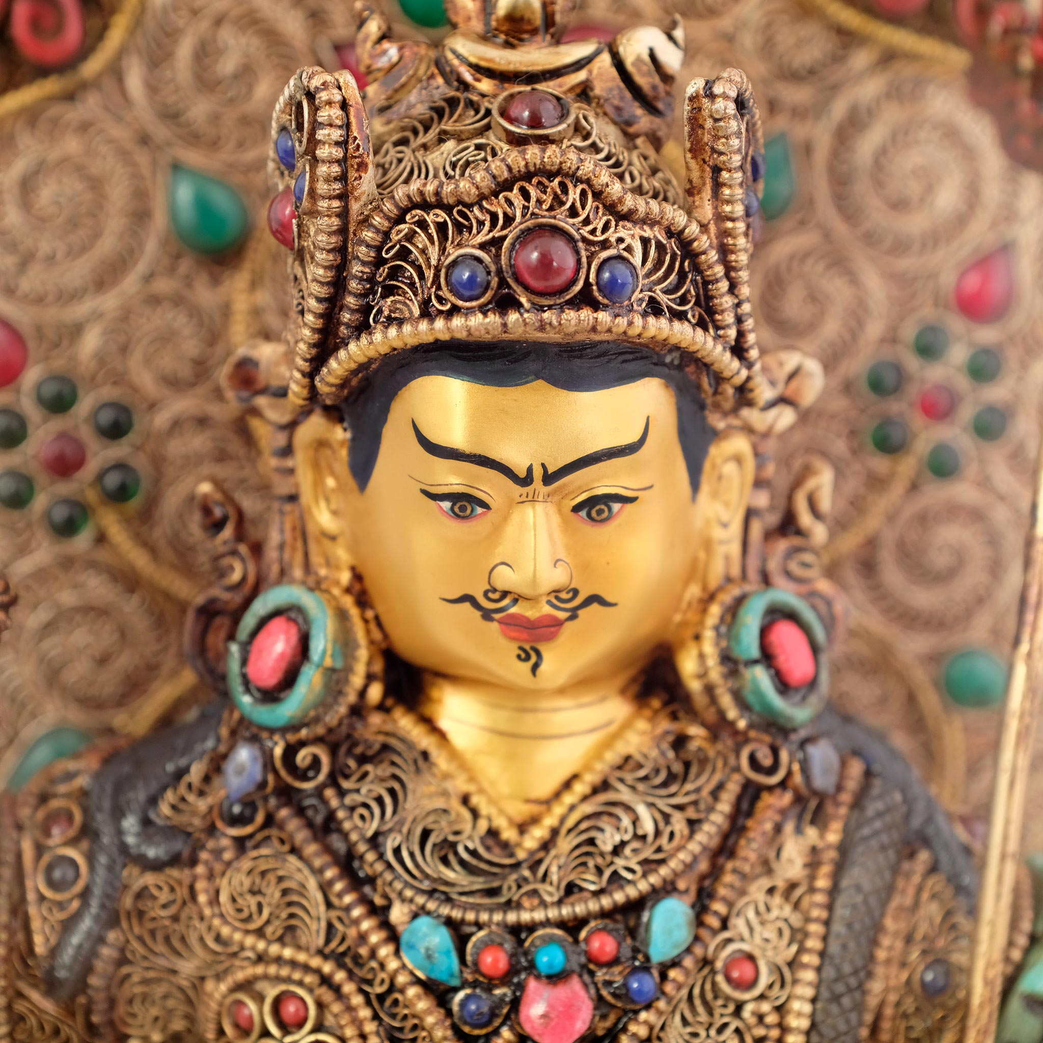 Detailansicht des Gesichts der Padmasambhava-Statue vor einer Aureole.