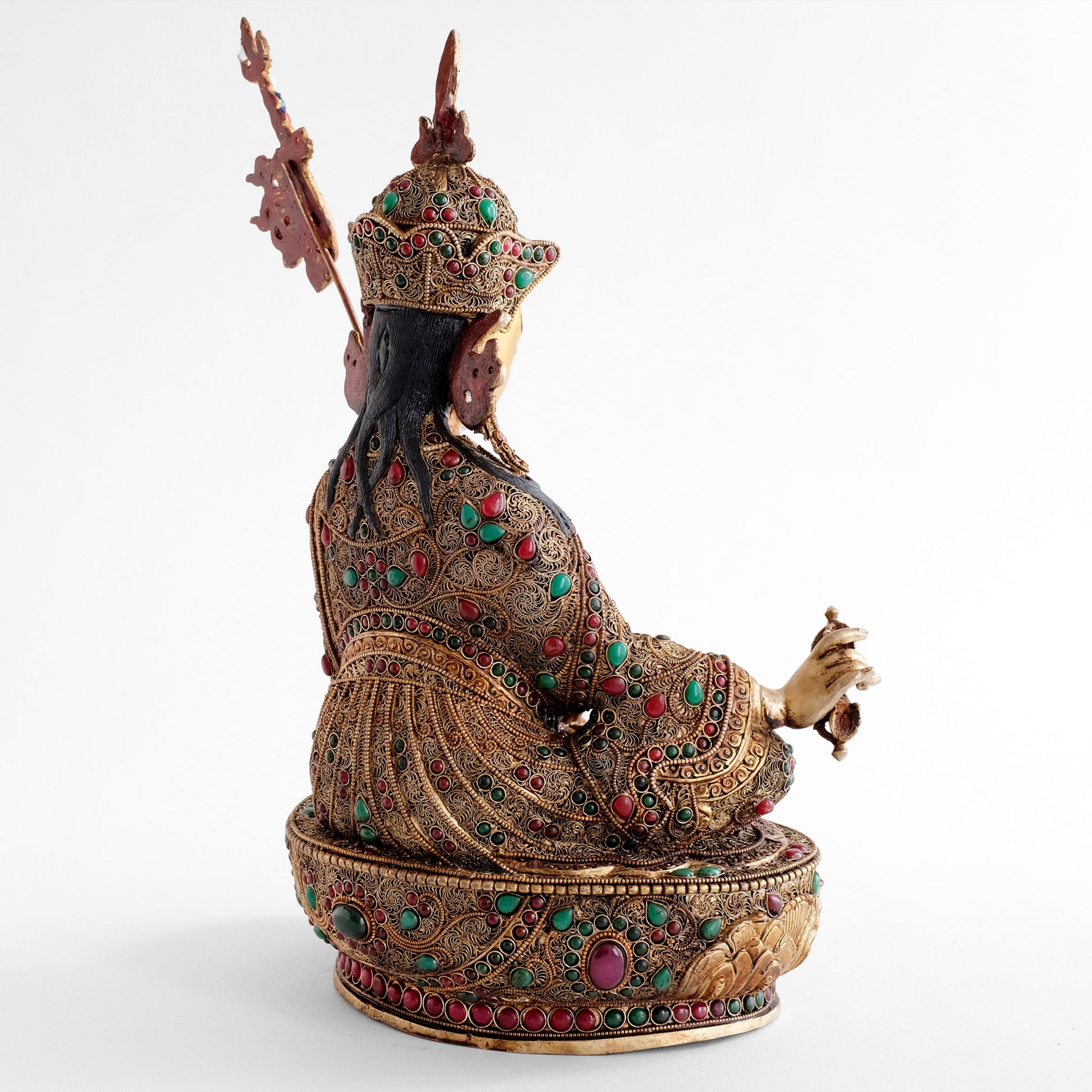 Padmasambhava, Guru Rinpoche Statue, er trägt eine königliche Robe, die mit feinen Filigran Ornamenten verziert und mit farbigen Steinen besetzt ist. Er sitzt auf einem Lotuspodest, das auf die gleiche Weise mit floralen Elementen verziert ist.