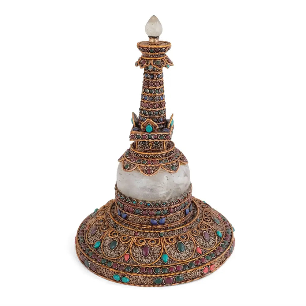 Runde Stupa aus Kupfer und Quartzkristall. Das Kupfer ist mit feinem Filigran in spiralförmigen Ornamenten besetzt, versilbert und vergoldet. Akzentuiert mit farbigen Steinen. 