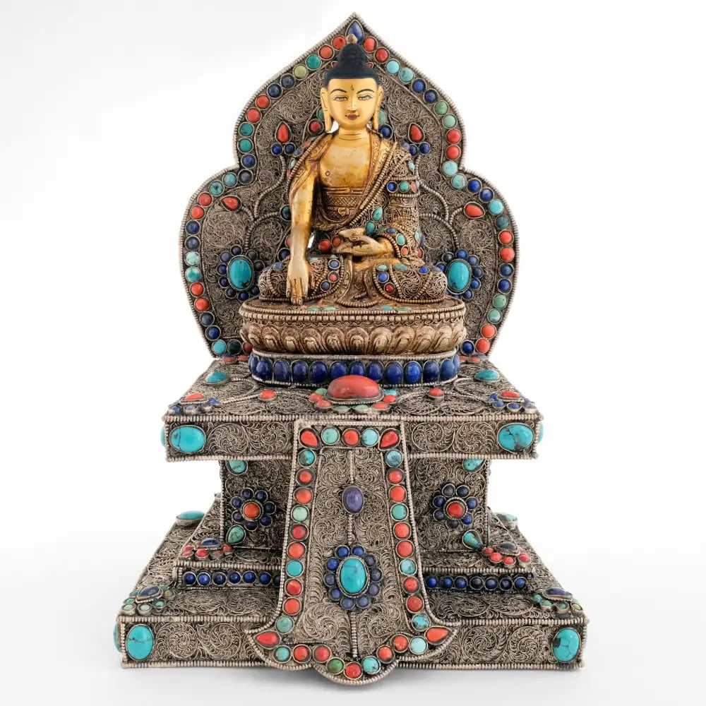 Shakyamuni Buddha statue auf einem mit Filgran geschmückten Thron mit Nimbus. Florale Ornamente sind mit natürlichen Steinen: Türkis, Koralle und Lapislazuli akzentuiert.  Das Gesicht ist in Gold gefasst.