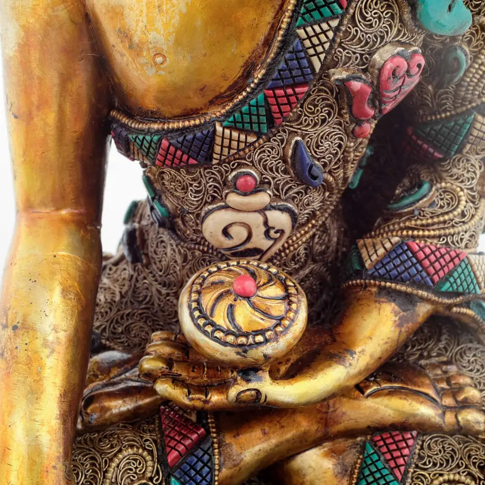 Die vergoldete Buddha Figur ist kunstvoll mit versilbertem Filigran verziert und geschnitzten farbigen Steinen.