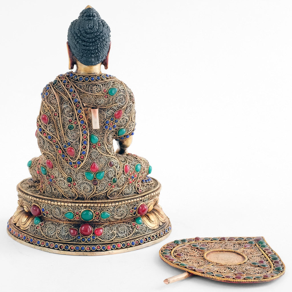 Die Shakyamuni Buddha Statue ist rückwärtig vollständig mit Filigran bearbeitet. Die Aureole liegt ausgesteckt vorn im Bild.