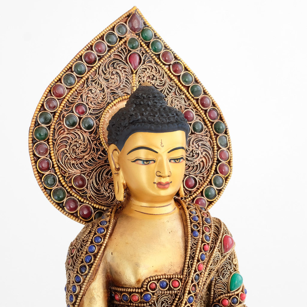 Shakyamuni Buddha Statue, Nahaufnahme des in Gold gesetzten Gesichts. Dahinter die tropfenförmige Aureole.