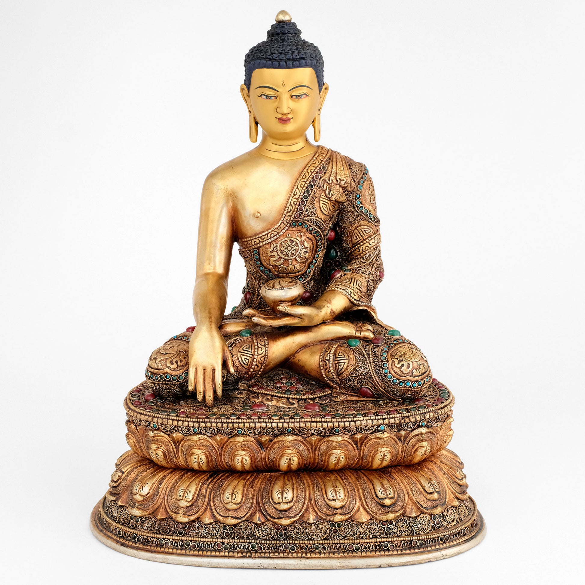 Die Shakyamuni Buddha Statue, sein Gewand und der Lotussockel sind mit Filigran Ornamenten verziert. Sie ist versilbert und vergoldet, mit farbigen Steinen verziert und für ein antikes Finish patiniert. Das Gesicht ist in Gold gefasst.