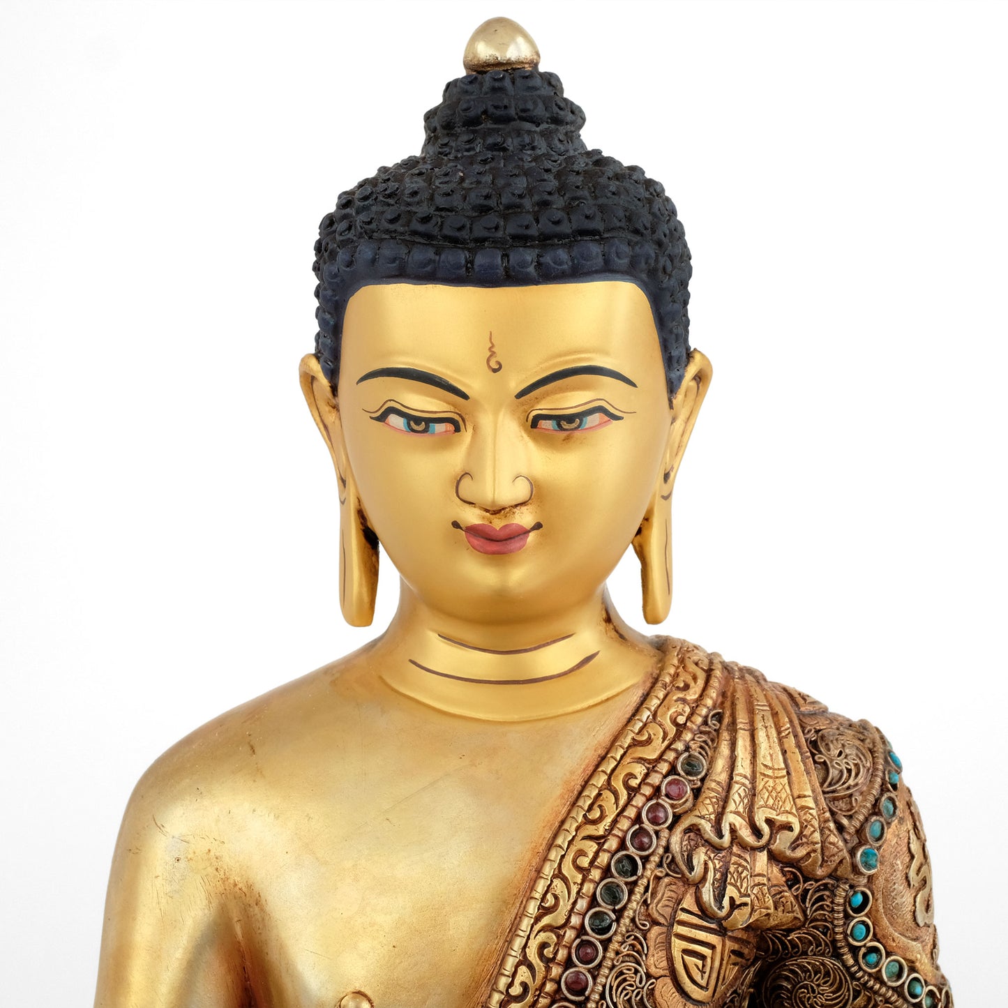 Shakyamuni Buddha, Siddhartha Gautama. Nahaufnahme von seinem Gesicht mit Urna zwischen den Augenbrauen. Das Gesicht hat eine Kaltgold Applikation, es ist bemalt.