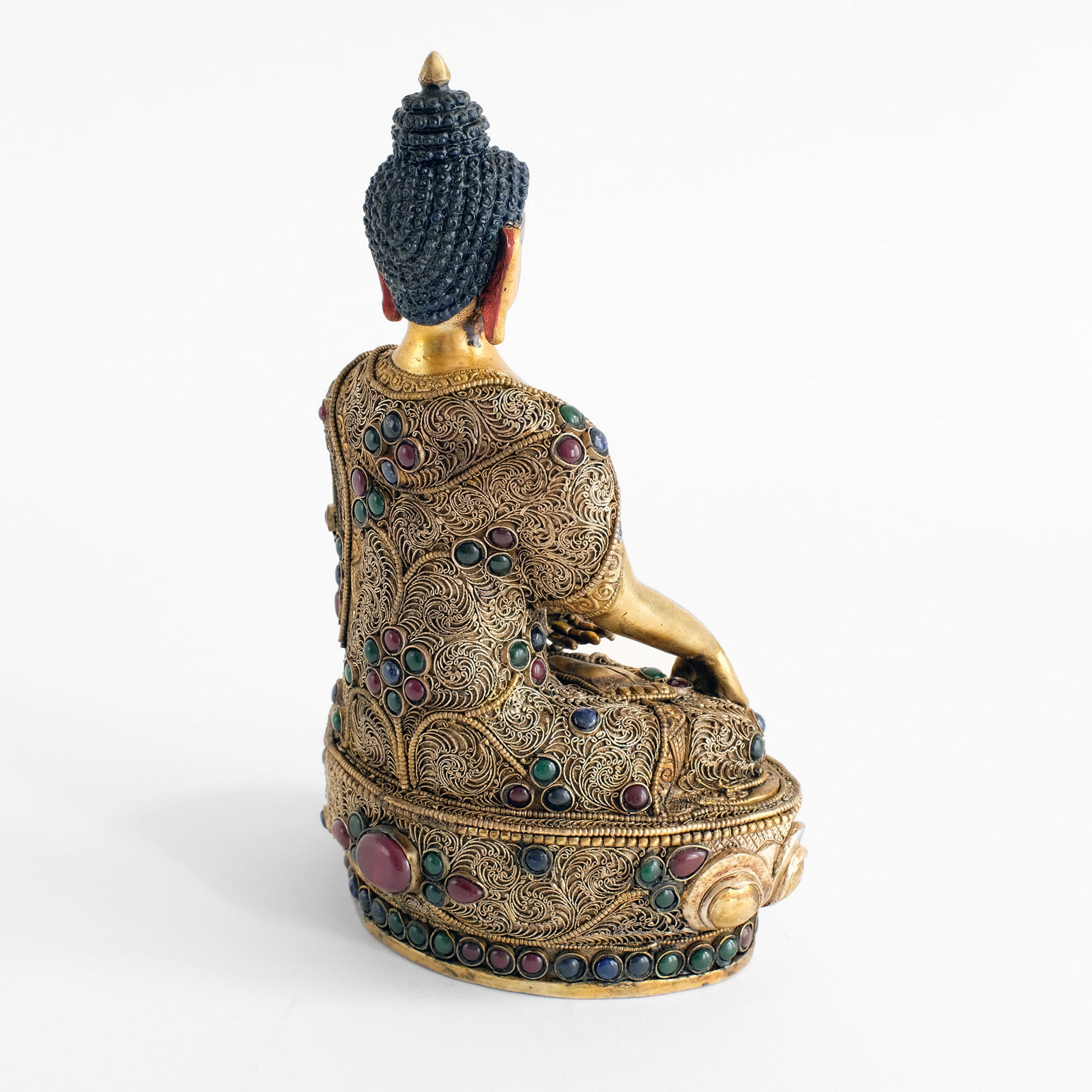 Rückansicht der Shakyamuni Buddha statue, mit feinen floralen Filigranornamenten, die Blüten werden von tief roten, blauen und grünen Steinen gebildet. Auch der untere Rand der Lotusthrons ist mit einer Reihe farbiger Steine gefasst.