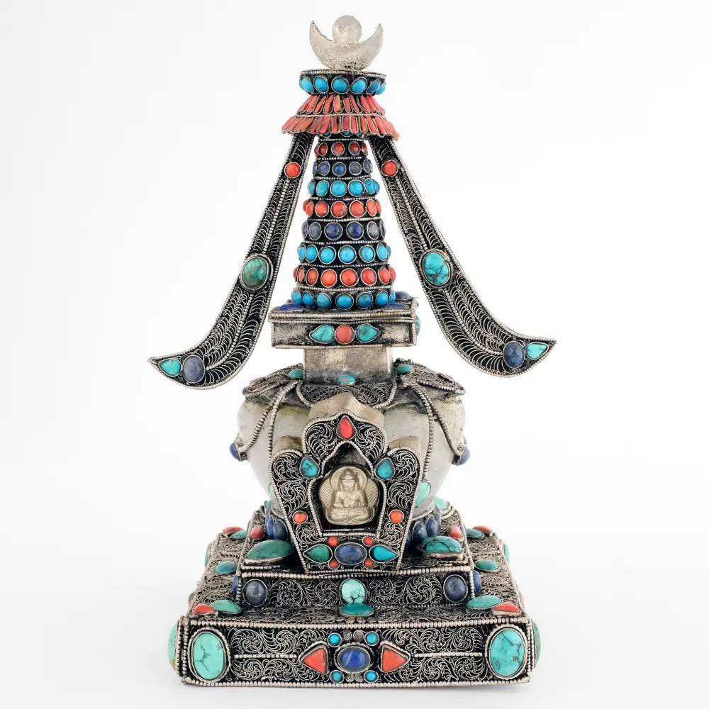 Stupa, in tibetischem Chörten, Vorderansicht. Sie ist aus Kupferplatten gefertigt, verziert mit feinen, spiralförmigen Filigranornamenten, versilbert und mit Edelsteinen besetzt. Die Kuppel ist aus Kristall.