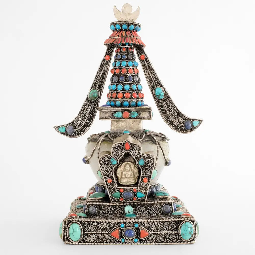 Stupa, in tibetischem Chörten, Vorderansicht. Sie ist aus Kupferplatten gefertigt, verziert mit feinen, spiralförmigen Filigranornamenten, versilbert und mit Edelsteinen besetzt. Die Kuppel ist aus Kristall.