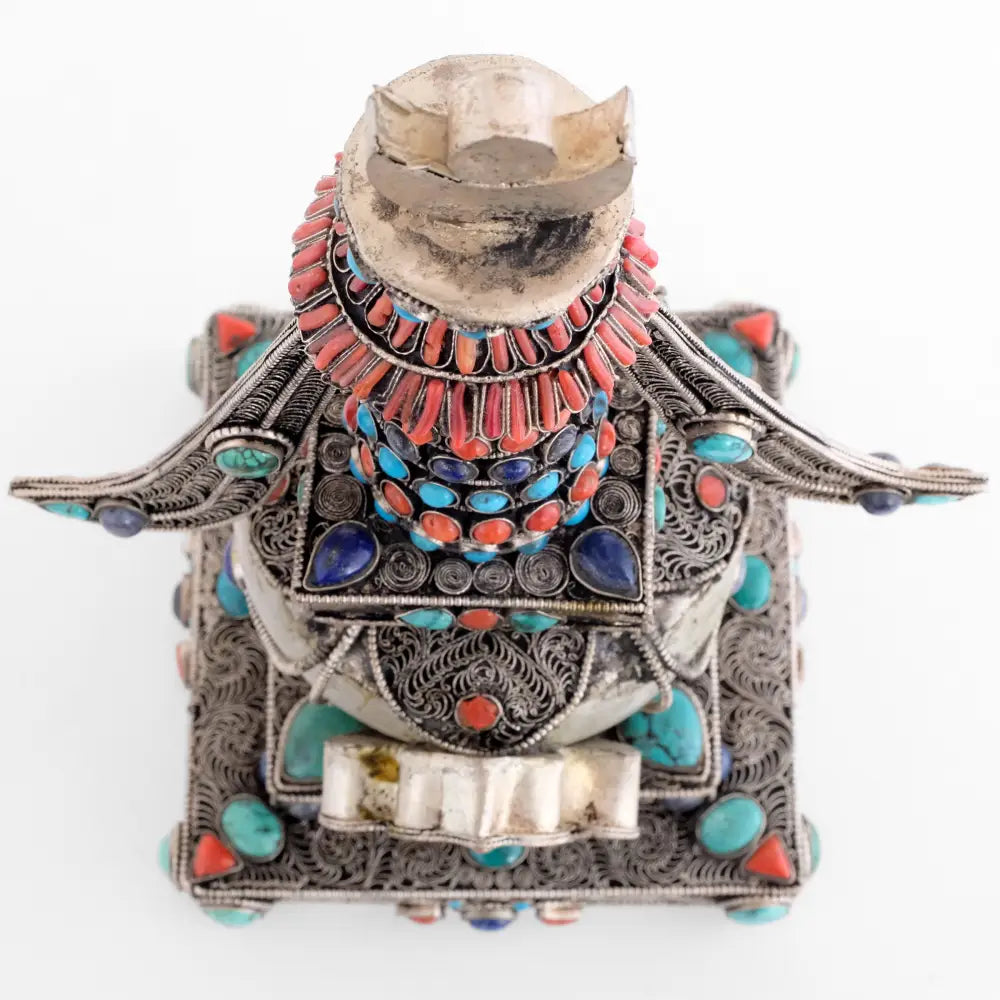 Stupa, Chorten, Ansicht von oben. Ihr Schirm ist mit Korallen verziert, die quadratische Harmika hat in jeder Ecke einen tropfenförmigen Lapislazuli-Stein, die Kuppel ist mit vier filigranen Bögen verziert, der quadratische Sockel ist ebenfalls mit in Spiralen angeordnetem Filigran verziert.