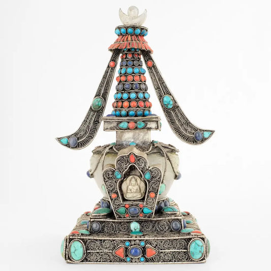 Stupa, in tibetischem Chörten, Vorderansicht. Sie ist aus Kupferplatten gefertigt, verziert mit feinen, spiralförmigen Filigranornamenten, versilbert und mit Edelsteinen besetzt. Die Kuppel ist aus Kristall.