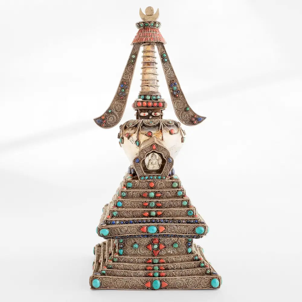 Die Stupa, die das buddhistische Universum repräsentiert, ist ein buddhistisches Heiligtum. Kupferblech und Kristall, mit Filigran verziert, versilbert, mit Türkis, Lapislazuli und Koralle besetzt. Der Kristall schenkt klare Gedanken und positive Energie. Höhe: 15" / 38 cm