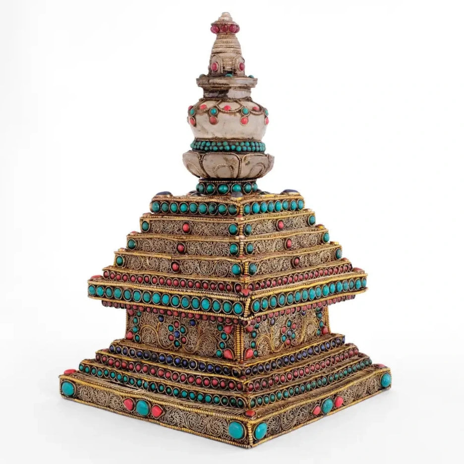 Stupa oder Chorten-Skulptur von einer Ecke aus gesehen. Die Stufen sind mit vergoldetem Perldraht umrahmt. Im Inneren dieses Rahmen sind feine Filigran-Spiralen angeordneten. Für den buddhistischen Hausaltar und als spirituelle Dekoration.