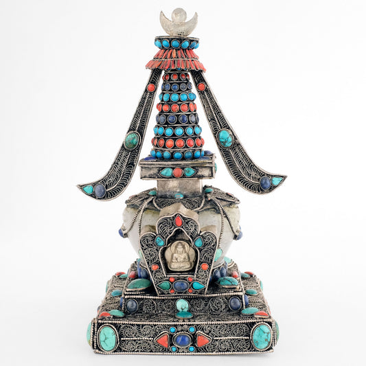 Stupa, in tibetischem Chörten, Vorderansicht. Sie ist aus Kupferplatten gefertigt, verziert mit feinen, spiralförmigen Filigranornamenten, versilbert und mit Edelsteinen besetzt. Die Kuppel ist aus Kristall.